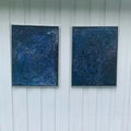 To innrammede malerier med dyp blå stjernehimmel i akryl og mixed media, fotografert mot hvit kledning. Ca. 50×70 cm per stykk. Art by Emerense