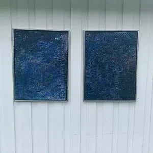 To innrammede malerier med dyp blå stjernehimmel i akryl og mixed media, fotografert mot hvit kledning. Ca. 50×70 cm per stykk. Art by Emerense