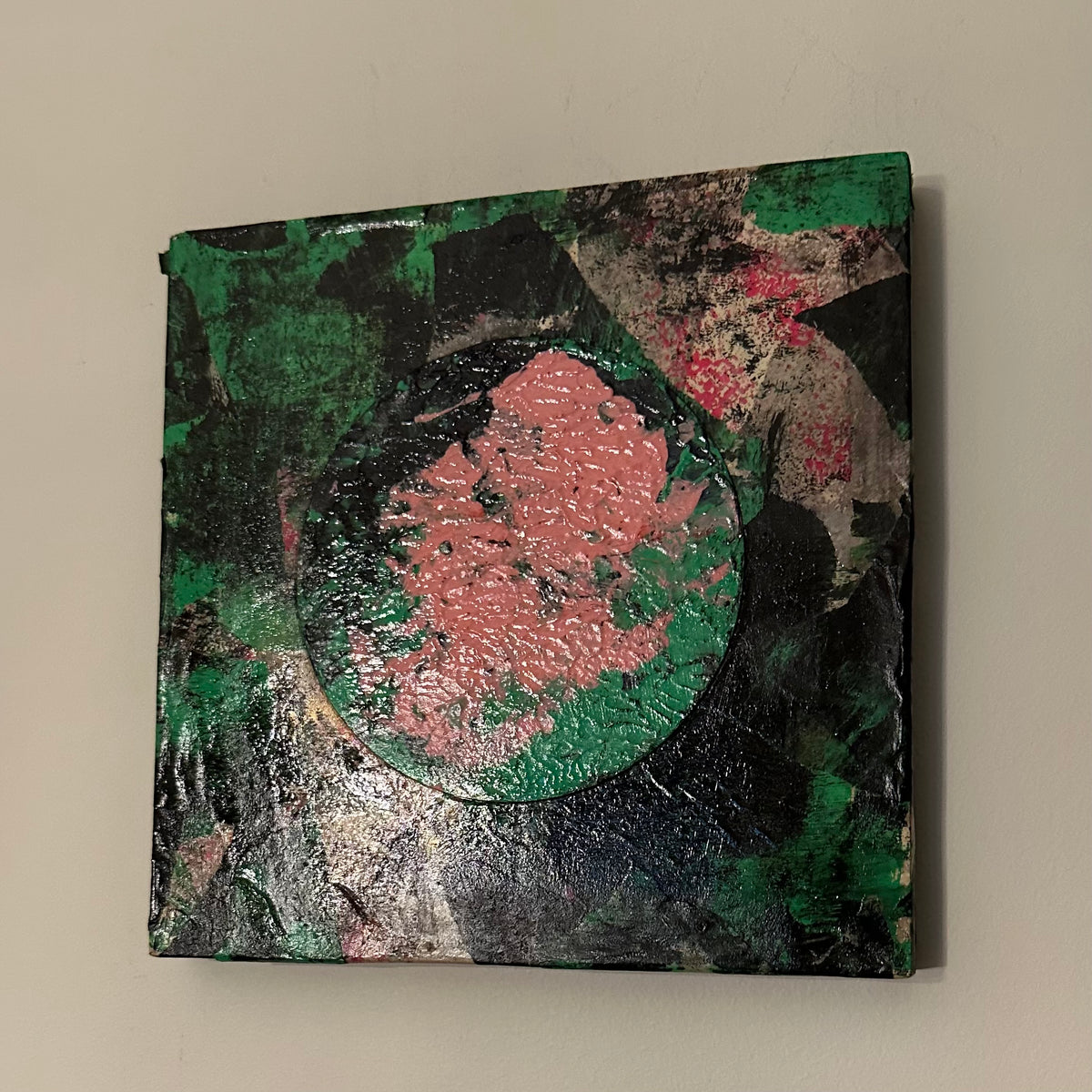 Eclipse I, rundt kunstverk i rosa og grønt på mørk collage, malt med akvarell og akryl, montert på treplate.