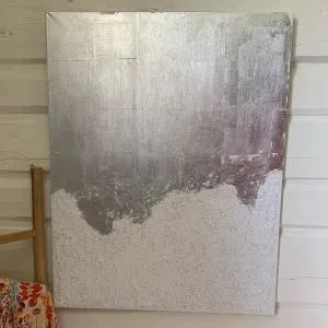 Rektangulært akrylmaleri, 50×70 cm, med abstrakt fjelllandskap i hvitt, grått og sølv med grov teksturert overflate. Fjellheimen av Art by Emerense