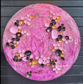 Rundt kunstverk ca. 40 cm med tredimensjonale rosa, sorte og gyldne halvkuler på teksturert rosa lerret. Pink Fantasy av Art by Emerense