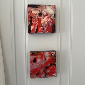 To kvadratiske kunstverk, 15×15 cm, hengt vertikalt med røde, sorte og metalliske penselstrøk i mix medium. Rød Inferno av Art by Emerense