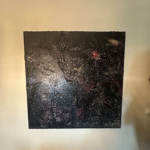 Stort kvadratisk kunstverk, 100×100 cm, hengt på hvit vegg. Mørk sort og dyp blåsvart strukturert overflate med sølvglitter og små lyspunkter som stjerner. Rød lys akkord øverst til høyre. The Big Bang, mixed media på lerret. Art by Emerense
