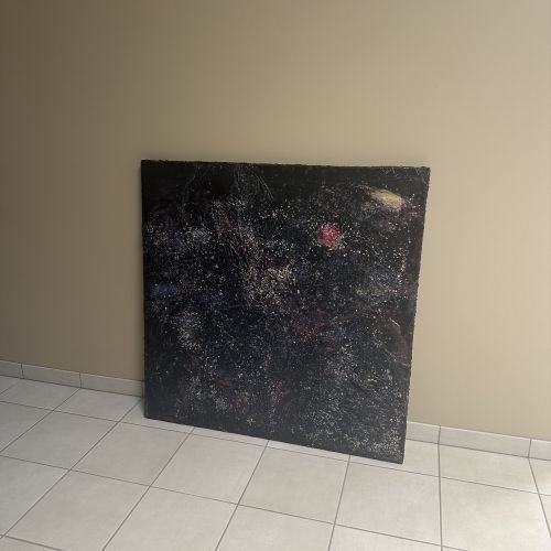 Stort kvadratisk kunstverk, 100×100 cm, stående på hvitt flisegulv mot beige vegg. Grov sort og mørkeblå struktur med glitrende sølv og hvite partikler spredt over hele flaten. Rødt lyspunkt øverst. The Big Bang av Art by Emerense
