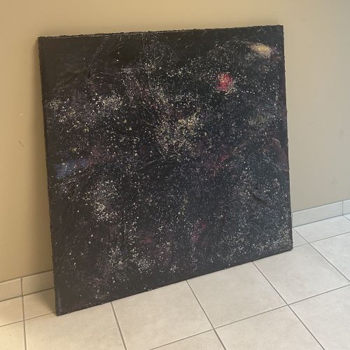 Stort kvadratisk kunstverk, 100×100 cm, stående på flisegulv i dagslys. Mørk sort overflate med tett glitrende sølv og hvite partikler i galakselignende mønster. Rødt lysglimt. The Big Bang av Art by Emerense
