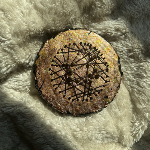 Rundt mixed media-kunstverk, 15 cm diameter, kobber og gull med sorte tråder og metallperler. Fotografert i naturlig lys på hvit fluffy overflate. Constellations II av Art by Emerense
