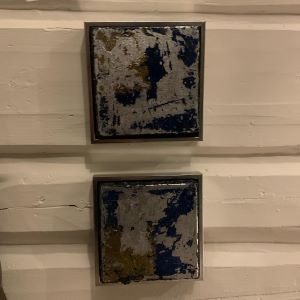 To innrammede kvadratiske kunstverk, 15×15 cm, hengt vertikalt på hvit vegg. Blå, gull og sort akryl med mixed media. Kvadratisk samspill av Art by Emerense